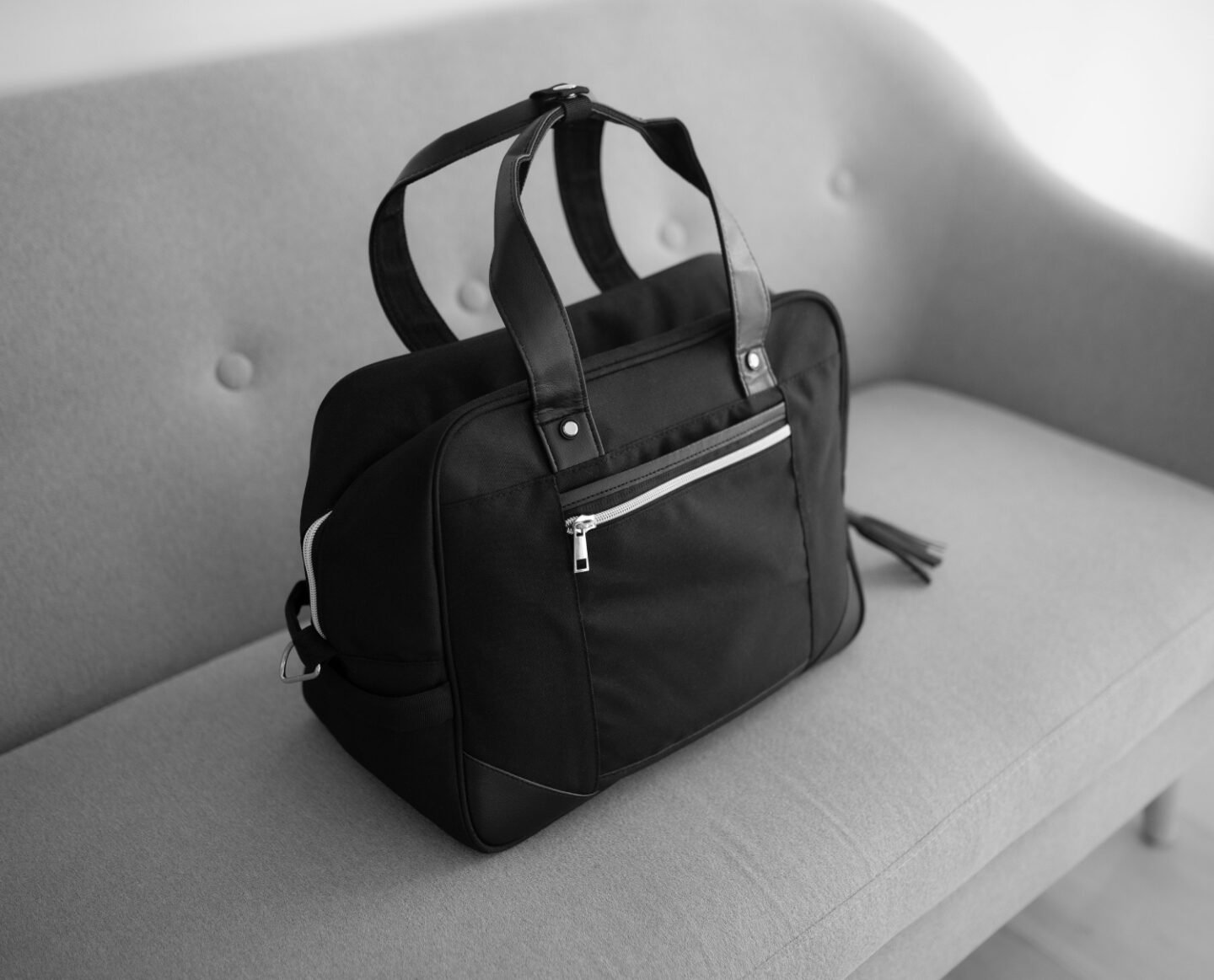 A picture of the Vela 24L Ladies Cabin Bag Holdall - 40x30x20 cm from CabinMax on a grey sofa in Spain.