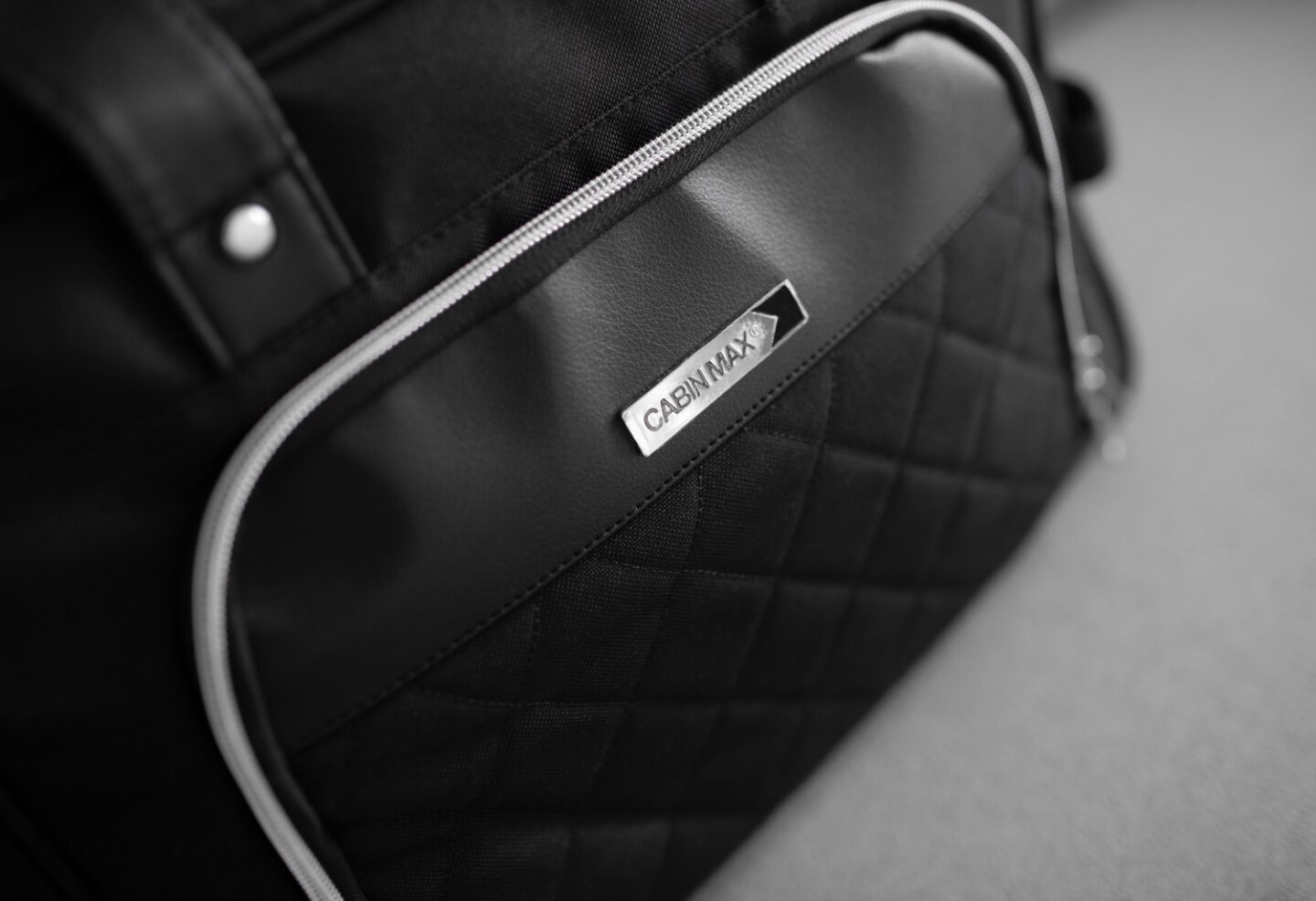 A close up picture of the Vela 24L Ladies Cabin Bag Holdall - 40x30x20 cm, on a grey sofa.