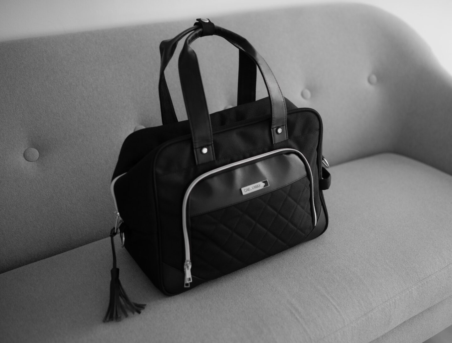 A picture of the CabinMax Vela 24L Ladies Cabin Bag Holdall - 40x30x20 cm, sitting on a grey sofa.